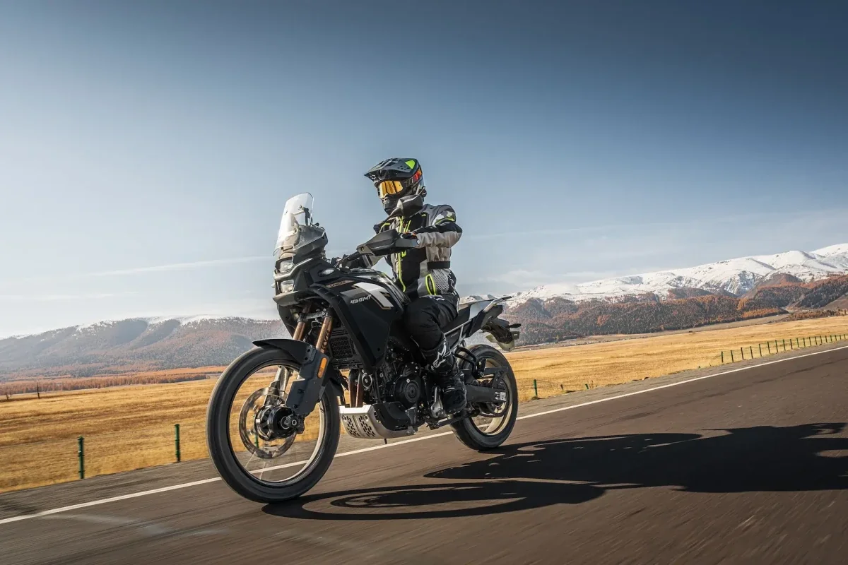 A rider on a CFMOTO adventure motorcycle on a scenic road
