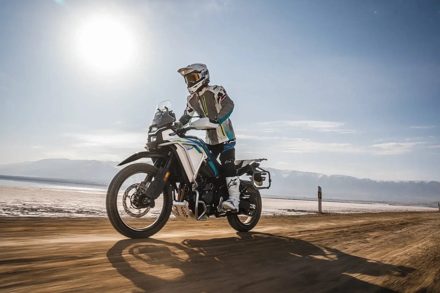 A CFMOTO motorcycle and rider travelling across an open landscape